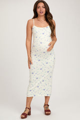 woman wearing a light yellow floral maternity dress and holding her baby bump