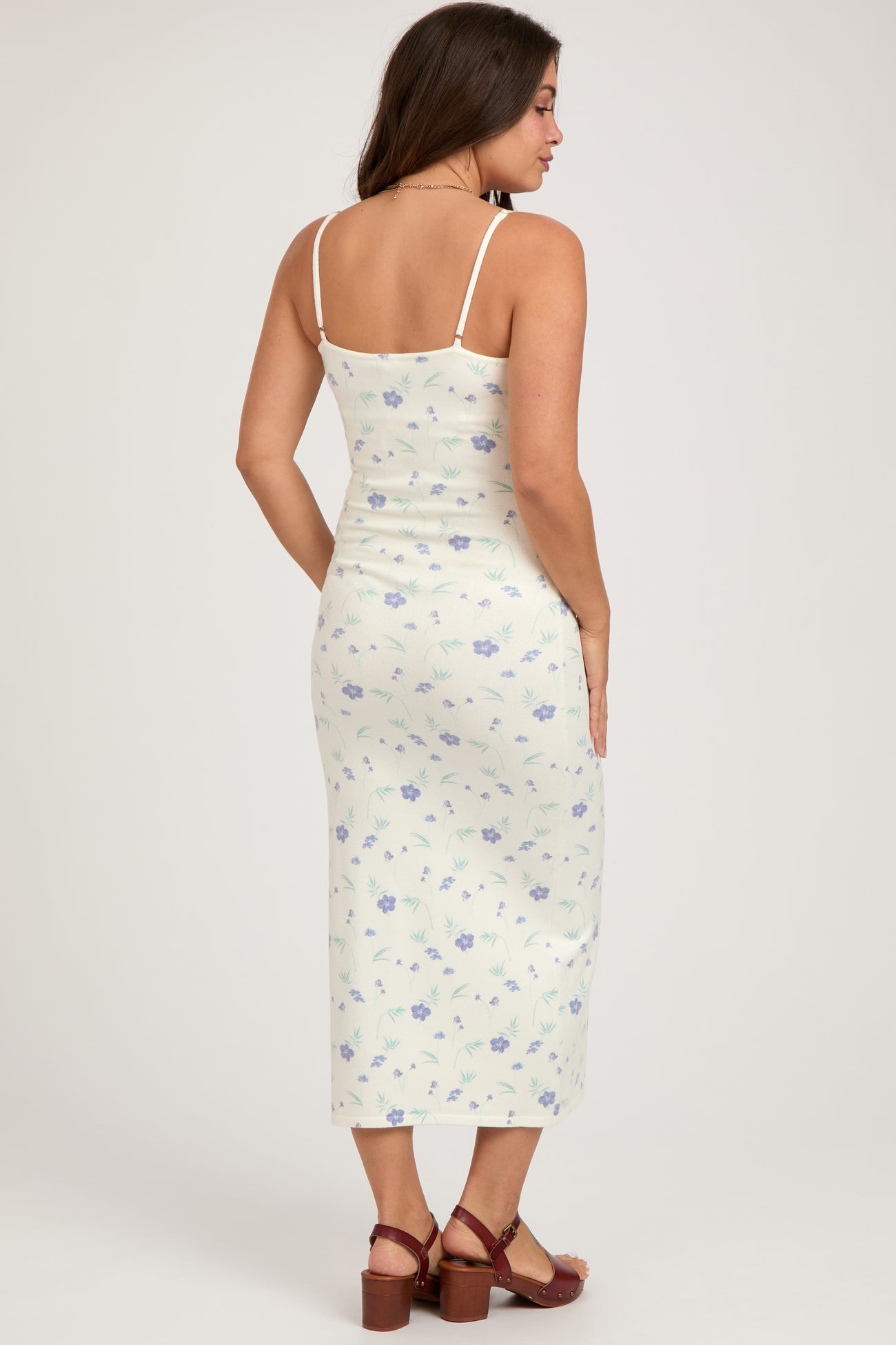 woman wearing a floral print maternity midi dress with spaghetti straps and a fitted silhouette