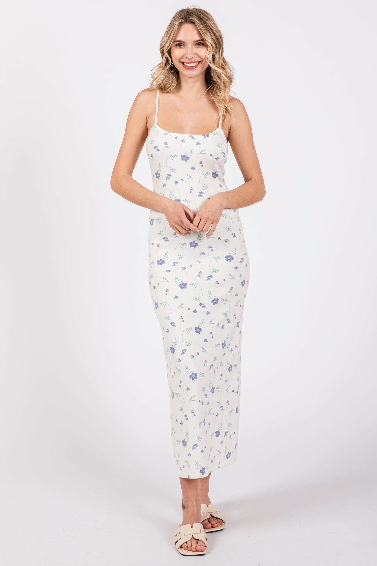 woman wearing a white floral print maxi dress with spaghetti straps and a fitted silhouette