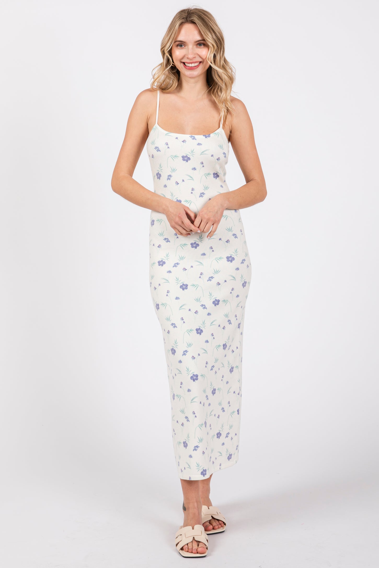 woman wearing a white floral print maxi dress with spaghetti straps and a fitted silhouette