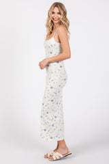 woman wearing a white floral print maxi dress with adjustable straps and side slits, standing sideways