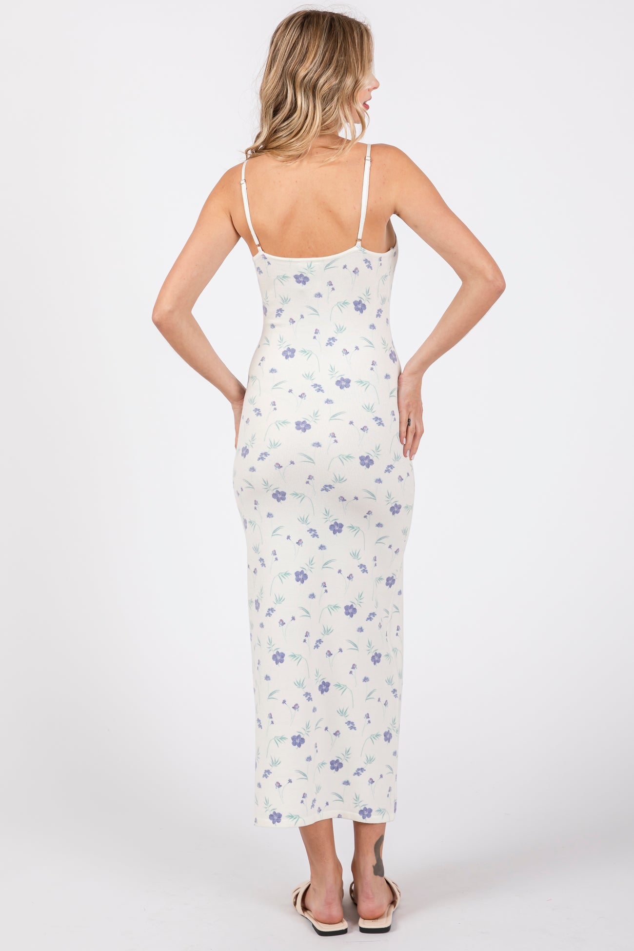 woman wearing a white floral long maxi dress with spaghetti straps, shown from the back