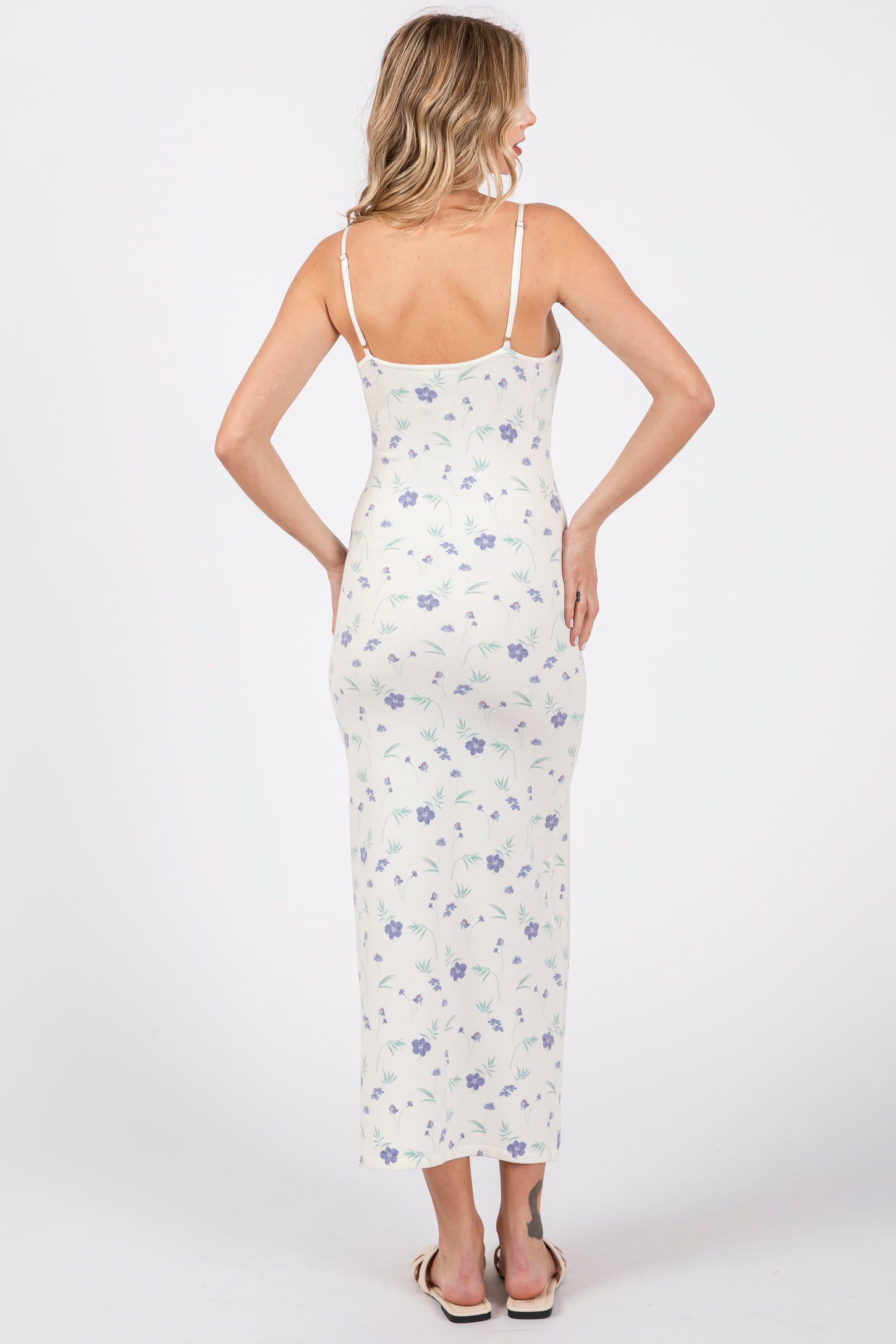 woman wearing a white floral long maxi dress with spaghetti straps, shown from the back