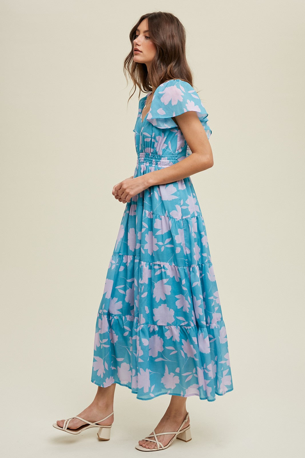 woman wearing a light blue floral maxi dress with puff sleeves and a smocked bodice, styled with strappy white sandals