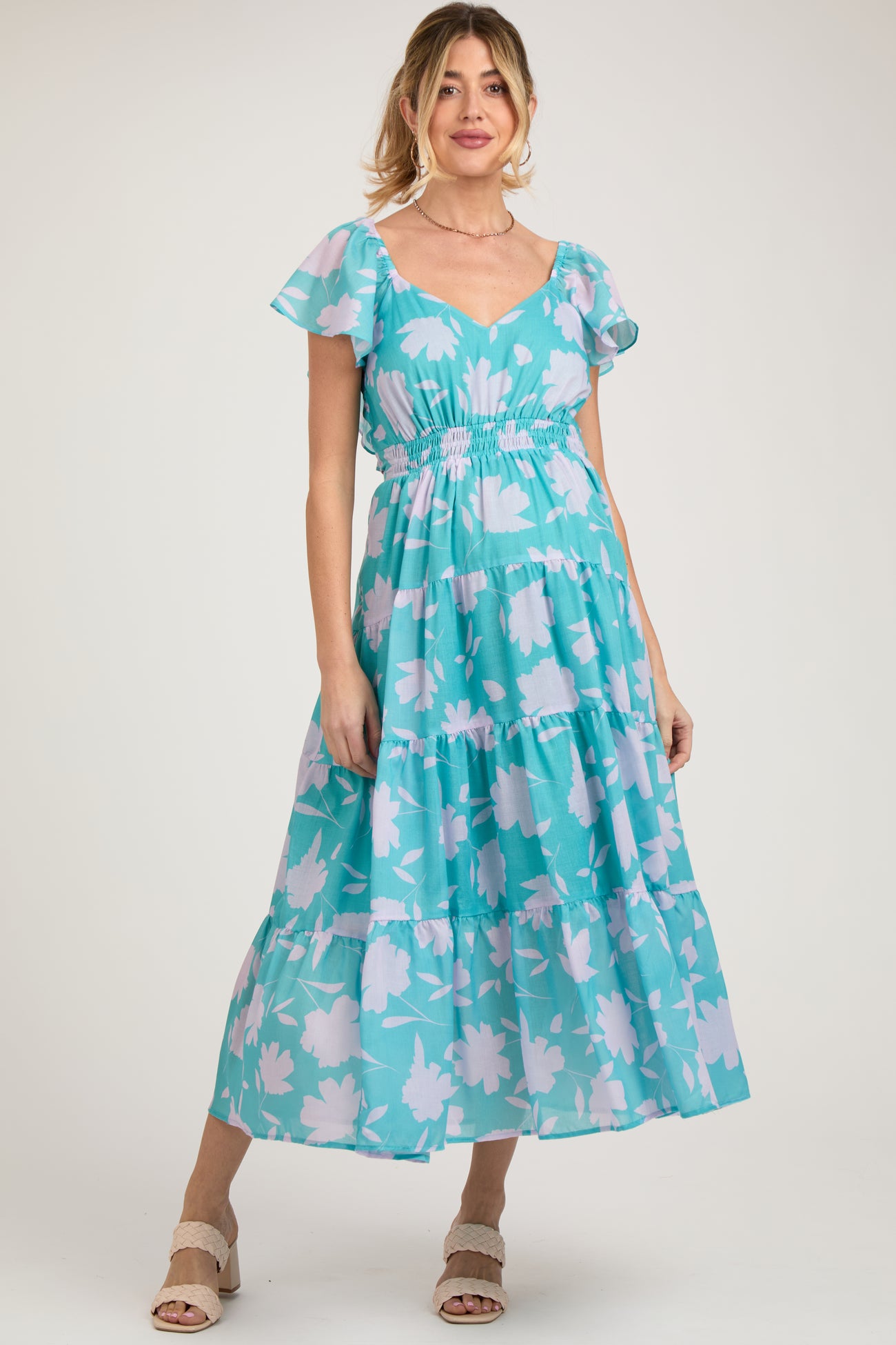 woman wearing a teal floral maternity maxi dress with short flutter sleeves and a smocked waist