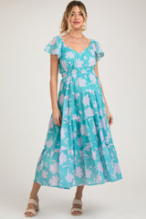 woman wearing a teal floral maternity maxi dress with short flutter sleeves and a smocked waist