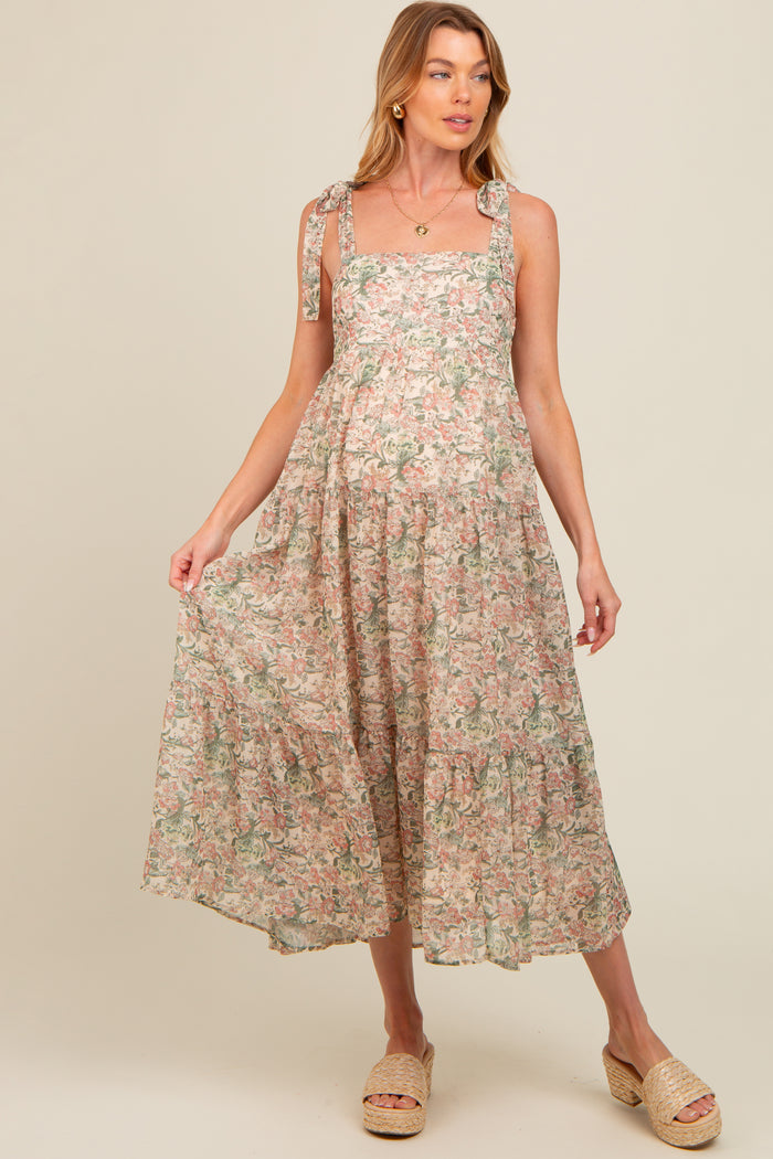 woman wearing a floral maternity maxi dress with tie straps and a flowing skirt, showcasing her baby bump