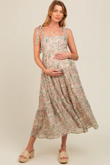 woman wearing a floral maternity dress with tie straps, posing and holding her baby bump