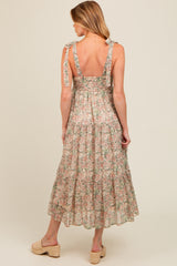 woman wearing a floral maternity maxi dress with tie shoulder straps and a smocked back, showing off her baby bump