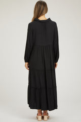 woman wearing a black maternity maxi dress with long sleeves and tiered ruffle details, showing a baby bump from behind