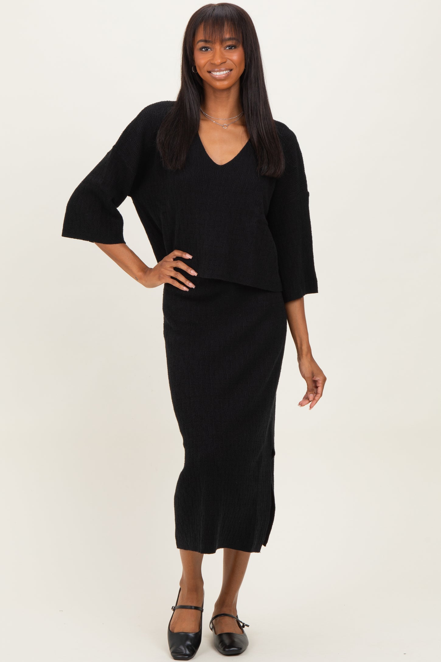 woman wearing a black two-piece ribbed knit outfit featuring a v-neck top and a midi skirt