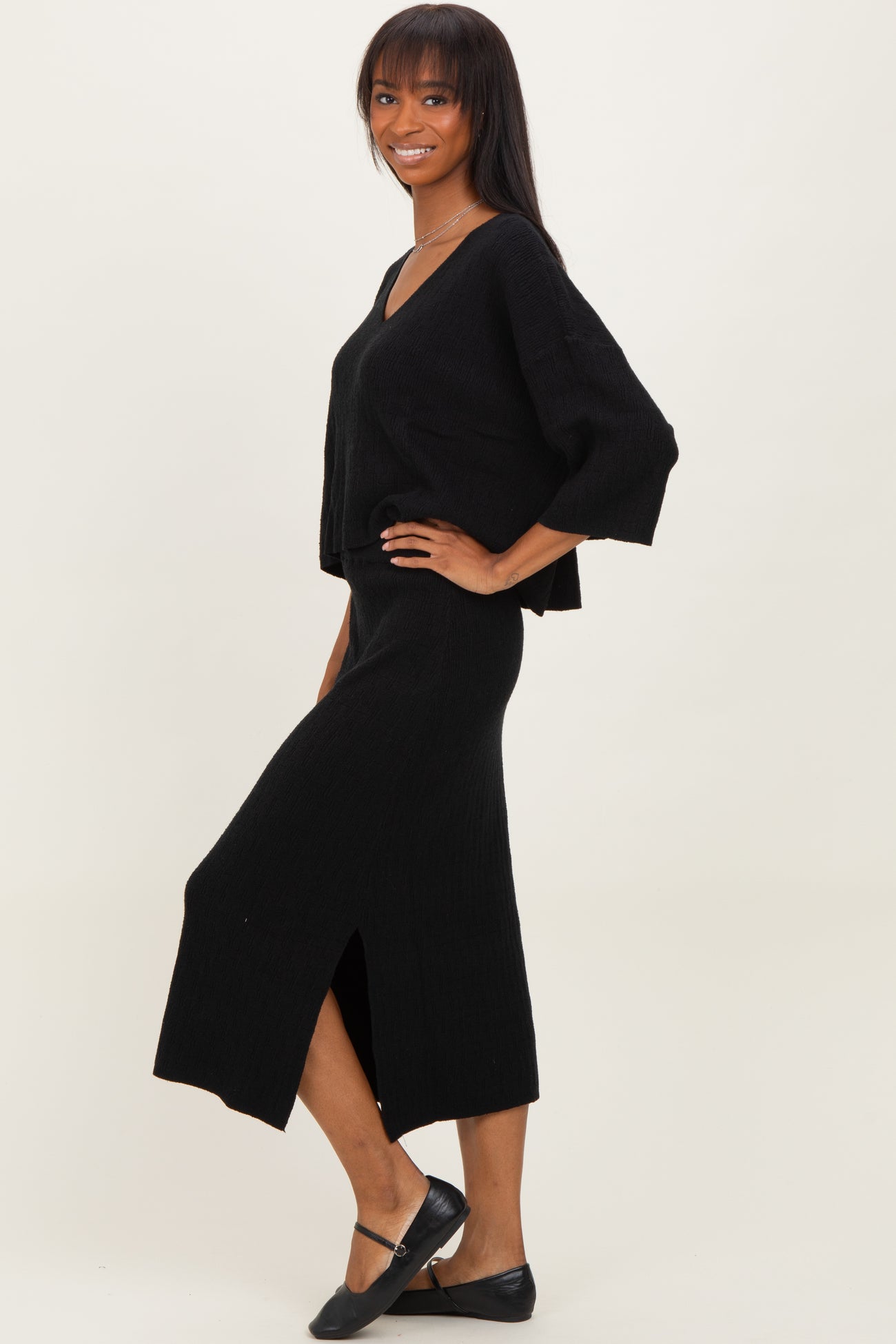 woman wearing a black ribbed two-piece sweater and skirt set with a v-neck and side slit on the skirt