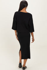 woman wearing a black ribbed two-piece set with a cropped top and midi skirt featuring a side slit