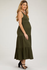 woman wearing a dark olive green maternity maxi dress with tiered ruffles and a visible baby bump