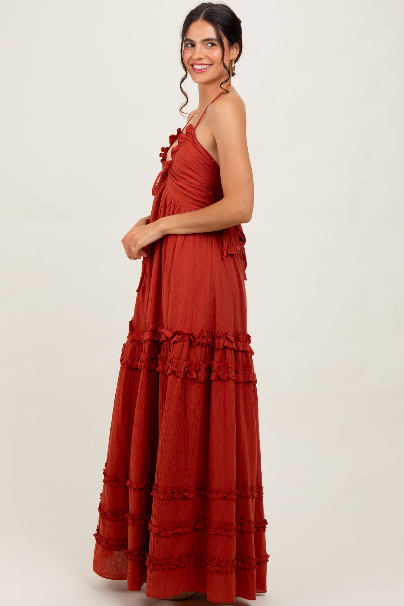 woman wearing a rust-colored maxi dress with ruffle details and adjustable straps