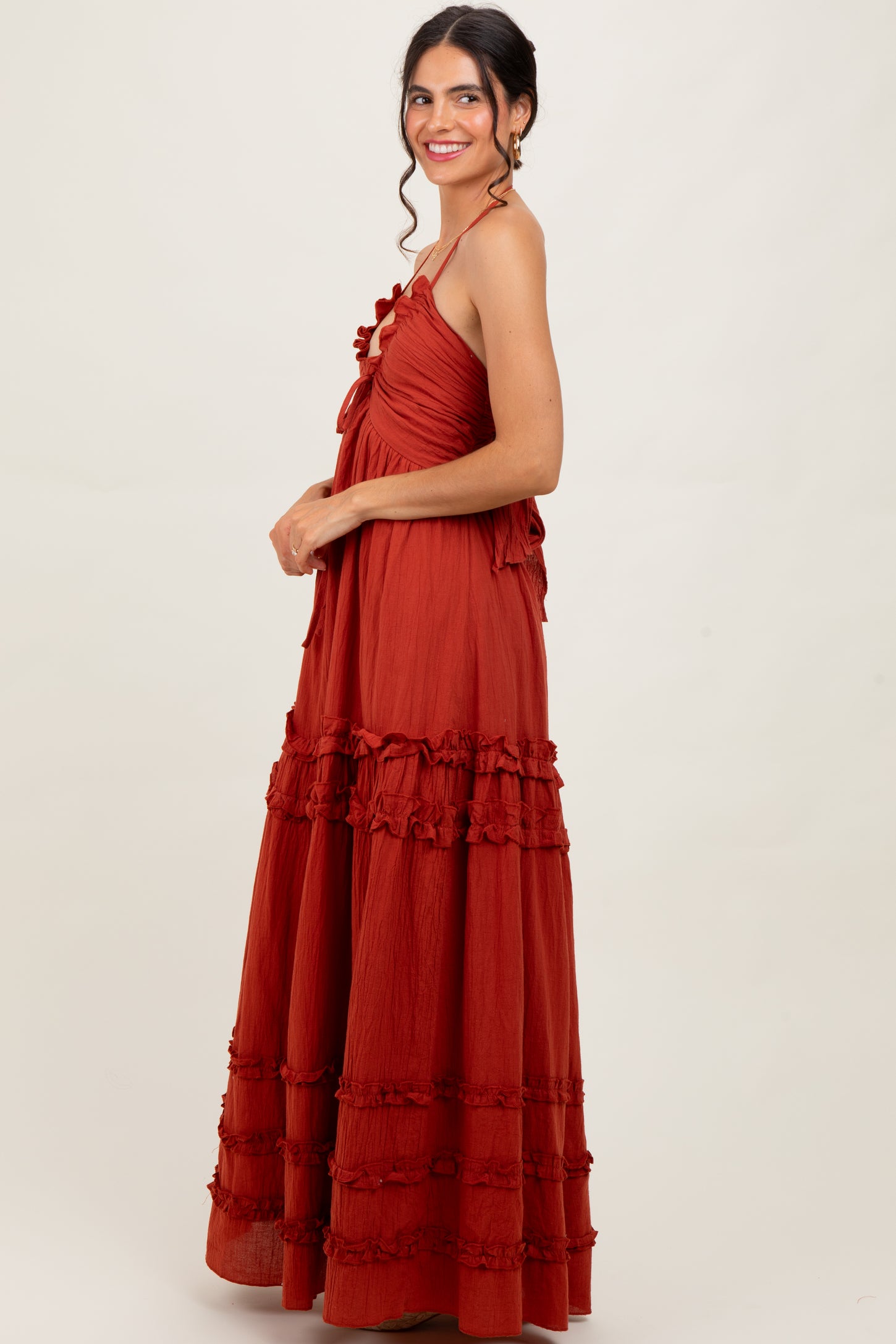 woman wearing a rust-colored maxi dress with ruffle details and adjustable straps