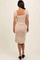 woman wearing a beige crochet maternity dress with short puff sleeves and a fitted silhouette, showing her baby bump from the back