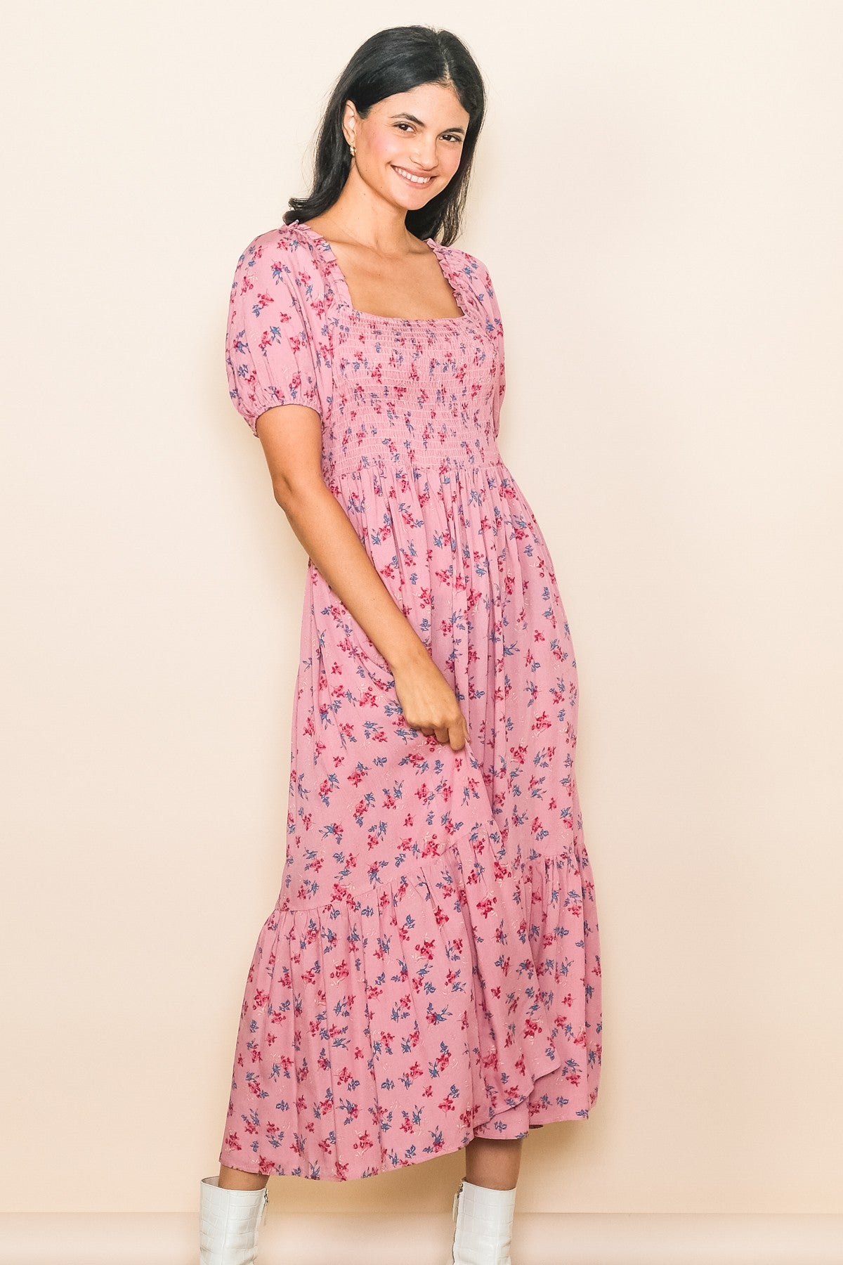 woman wearing a pink floral midi dress with puff sleeves and a square neckline, smiling against a neutral background