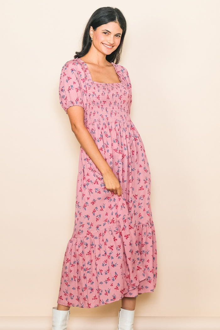 woman wearing a pink floral midi dress with puff sleeves and a square neckline, smiling against a neutral background
