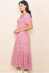 woman wearing a pink floral puff sleeve midi dress with a smocked bodice and ruffled hem