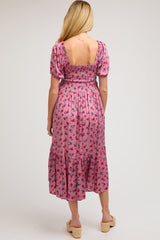 woman wearing a floral pink maternity midi dress with a smocked bodice and puff sleeves, showing her back