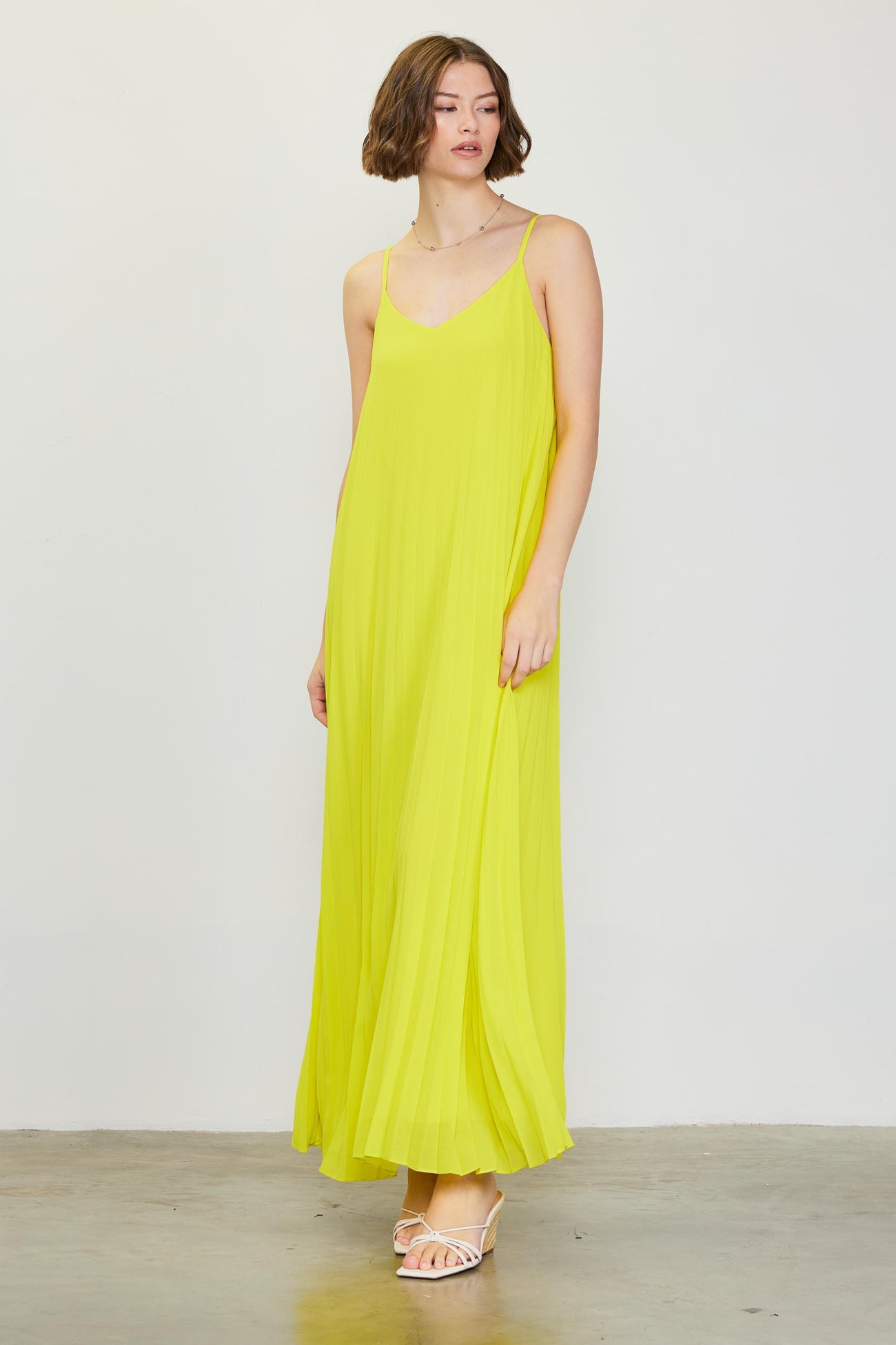 woman wearing a bright yellow maxi dress with thin straps and a flowing design