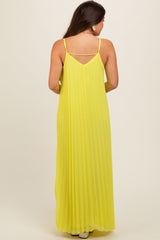 woman wearing a long yellow pleated maternity dress with adjustable straps, showing the back view and flowing silhouette