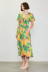 woman wearing a colorful floral midi dress with puff sleeves and a tie front detail