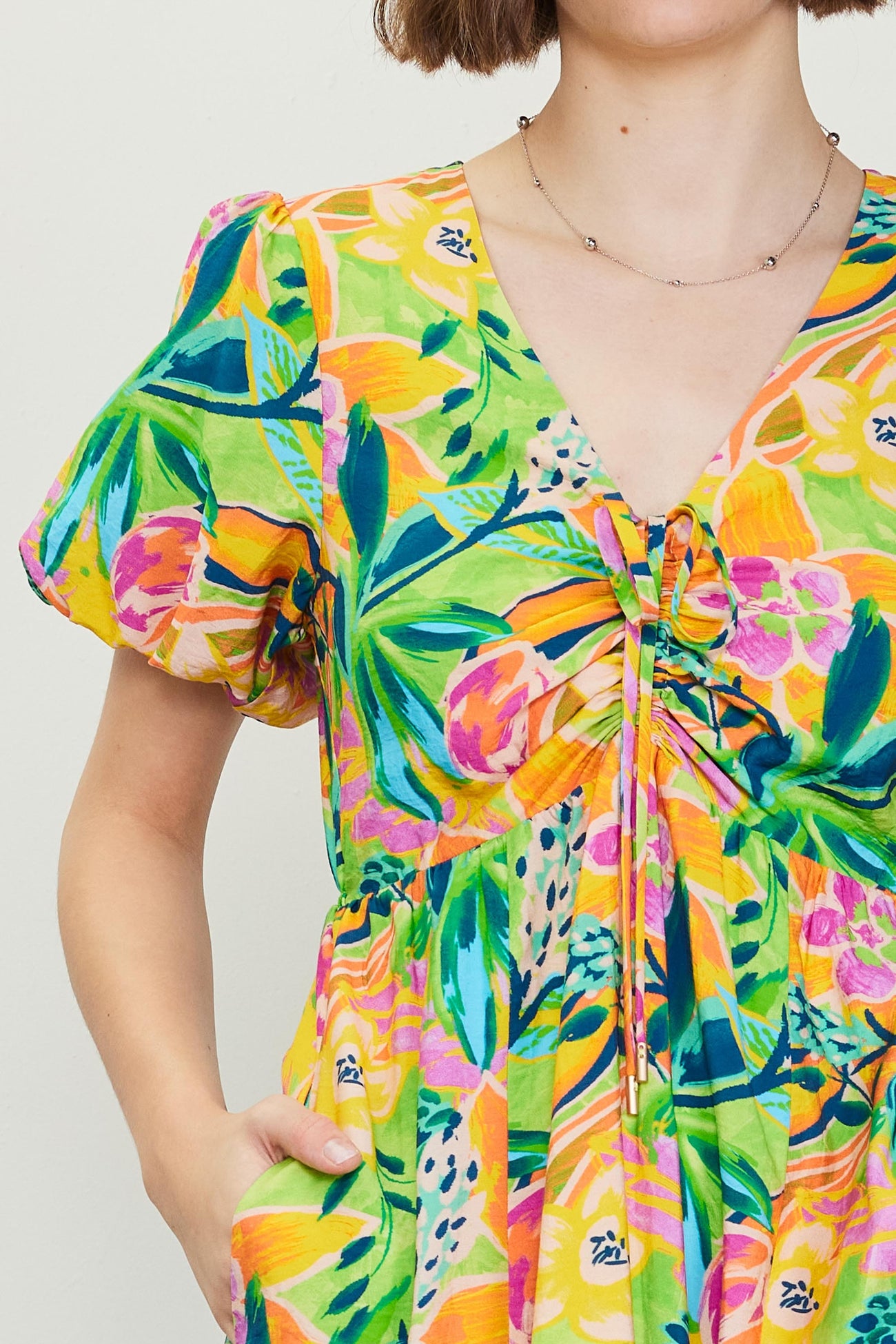 woman wearing a colorful floral print dress with short puff sleeves and a drawstring detail at the neckline