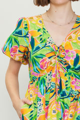 woman wearing a colorful floral print dress with short puff sleeves and a drawstring detail at the neckline