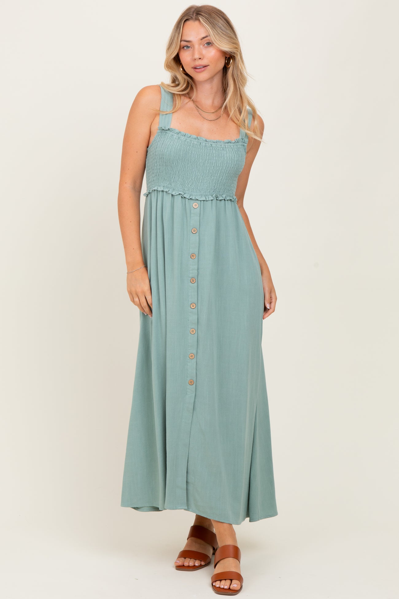 woman wearing a sage green smocked bodice maxi dress with buttons and straps