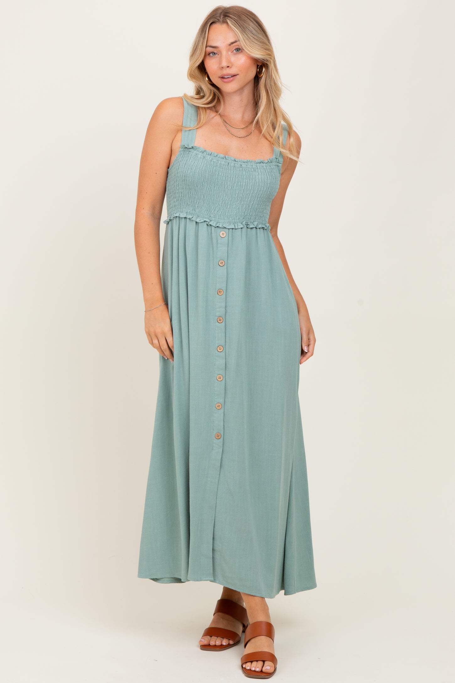 woman wearing a sage green smocked bodice maxi dress with buttons and straps