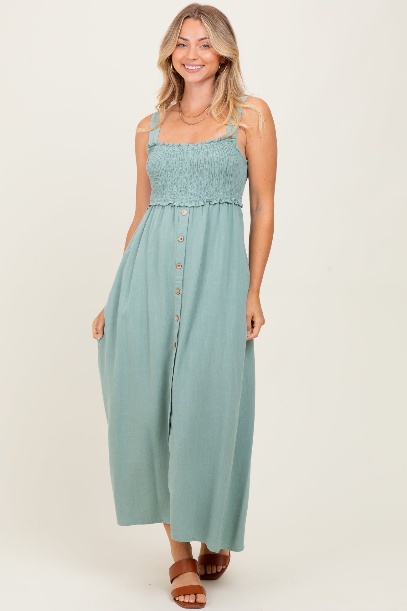 woman wearing a teal smocked bodice maxi dress with button detailing and adjustable straps