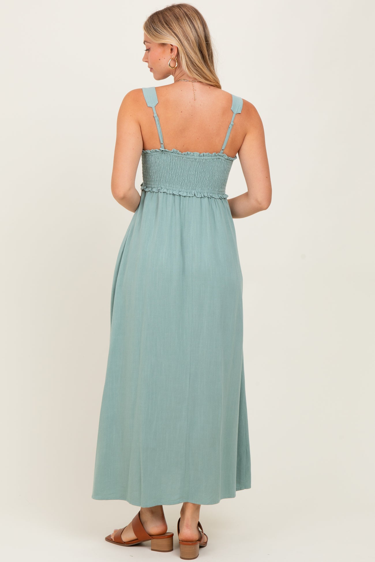 woman wearing a light teal maxi dress with smocked bodice and adjustable straps, seen from the back