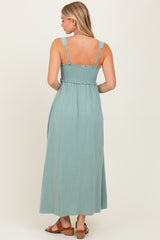 woman wearing a light teal maxi dress with smocked bodice and adjustable straps, seen from the back