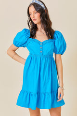 woman wearing a bright blue puff sleeve mini dress with a ruffled hem and button details