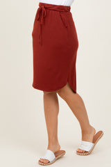 woman wearing a rust-colored drawstring midi skirt with side pockets and a slight asymmetrical hem