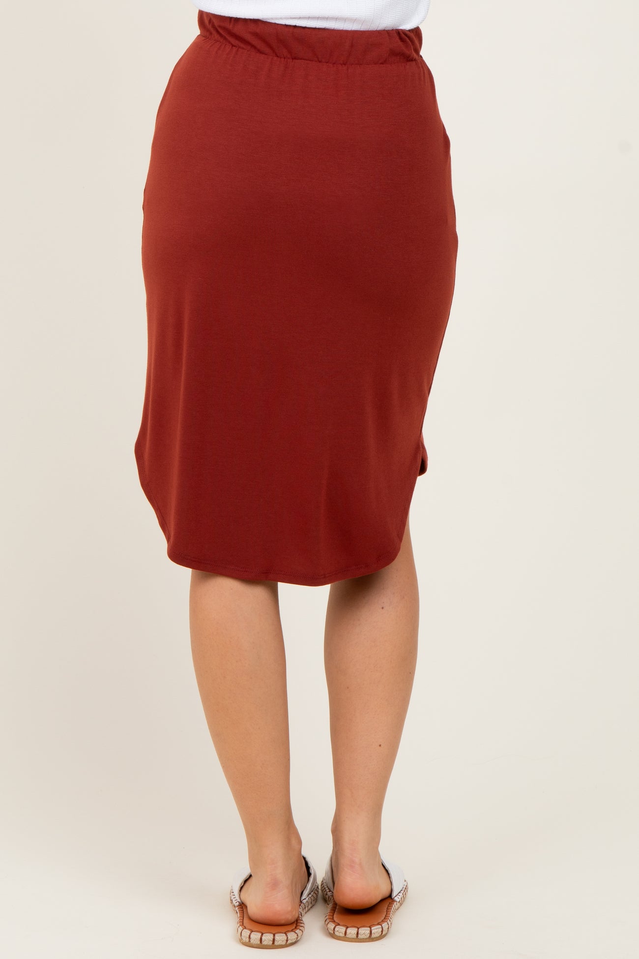 woman wearing a rust-colored knee-length skirt with an elastic waistband and a curved hemline
