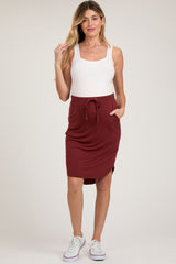 woman wearing a white maternity tank top and a burgundy maternity skirt with a drawstring and pockets