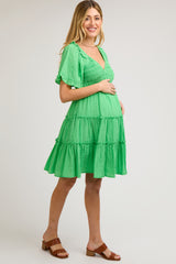 woman wearing a green tiered maternity dress with short sleeves and a baby bump visible