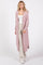 woman wearing a light pink long cardigan with pockets, paired with a white tank top and cream wide-leg pants