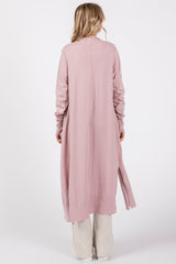 woman wearing a long sleeve light pink cardigan with a side slit, shown from the back