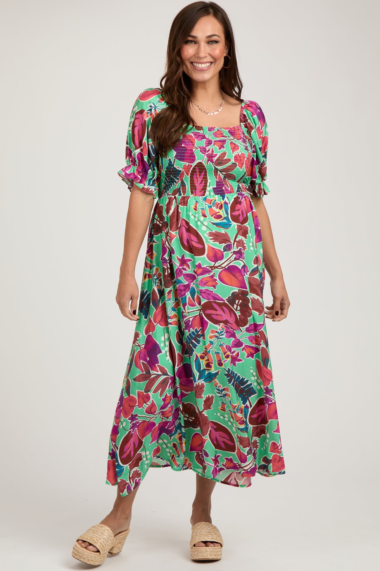 woman wearing a colorful floral print maternity dress with puff sleeves and a smocked bodice, featuring a flowy skirt