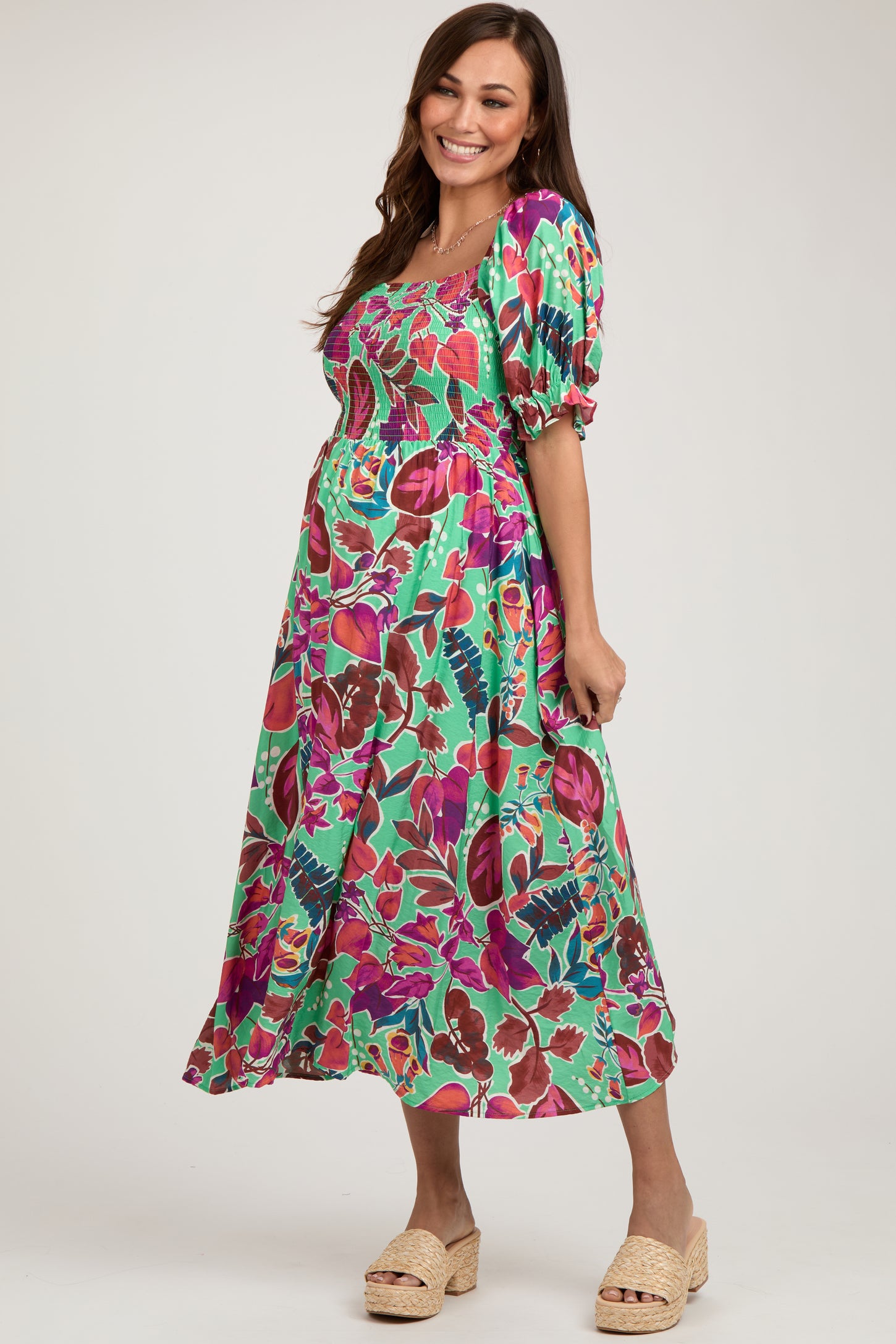 woman wearing a green floral maternity dress with puff sleeves and a fitted bodice, showing her baby bump