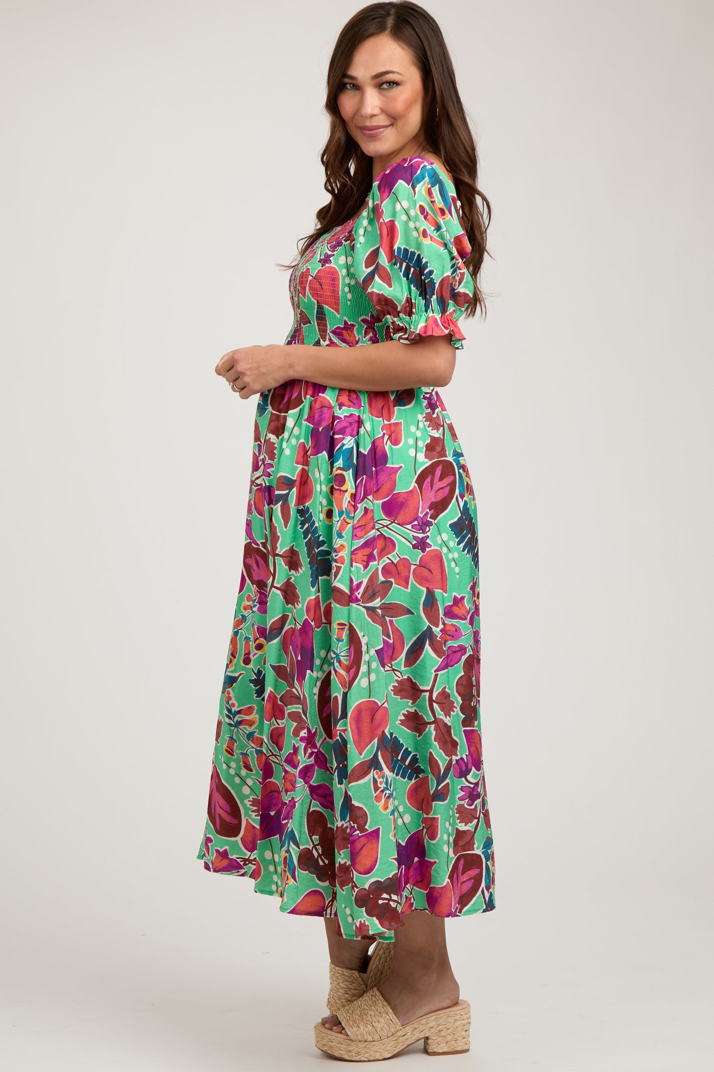 woman wearing a colorful floral maxi maternity dress with puff sleeves and a visible baby bump