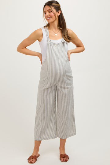 woman wearing a striped maternity overall jumpsuit with wide legs and a white tank top, showing her baby bump