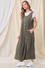 woman wearing a green ribbed maxi dress with buttons and pockets over a white t-shirt, paired with white sneakers