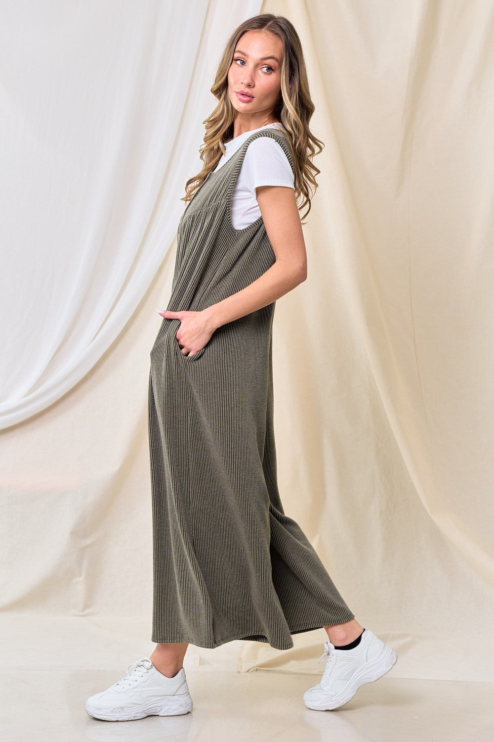 woman wearing a long olive green ribbed jumper dress over a white t-shirt, styled with white sneakers