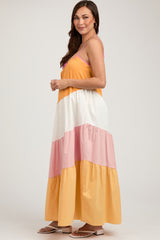 woman wearing a colorful maternity maxi dress with yellow, white, and pink tiers, showcasing her baby bump