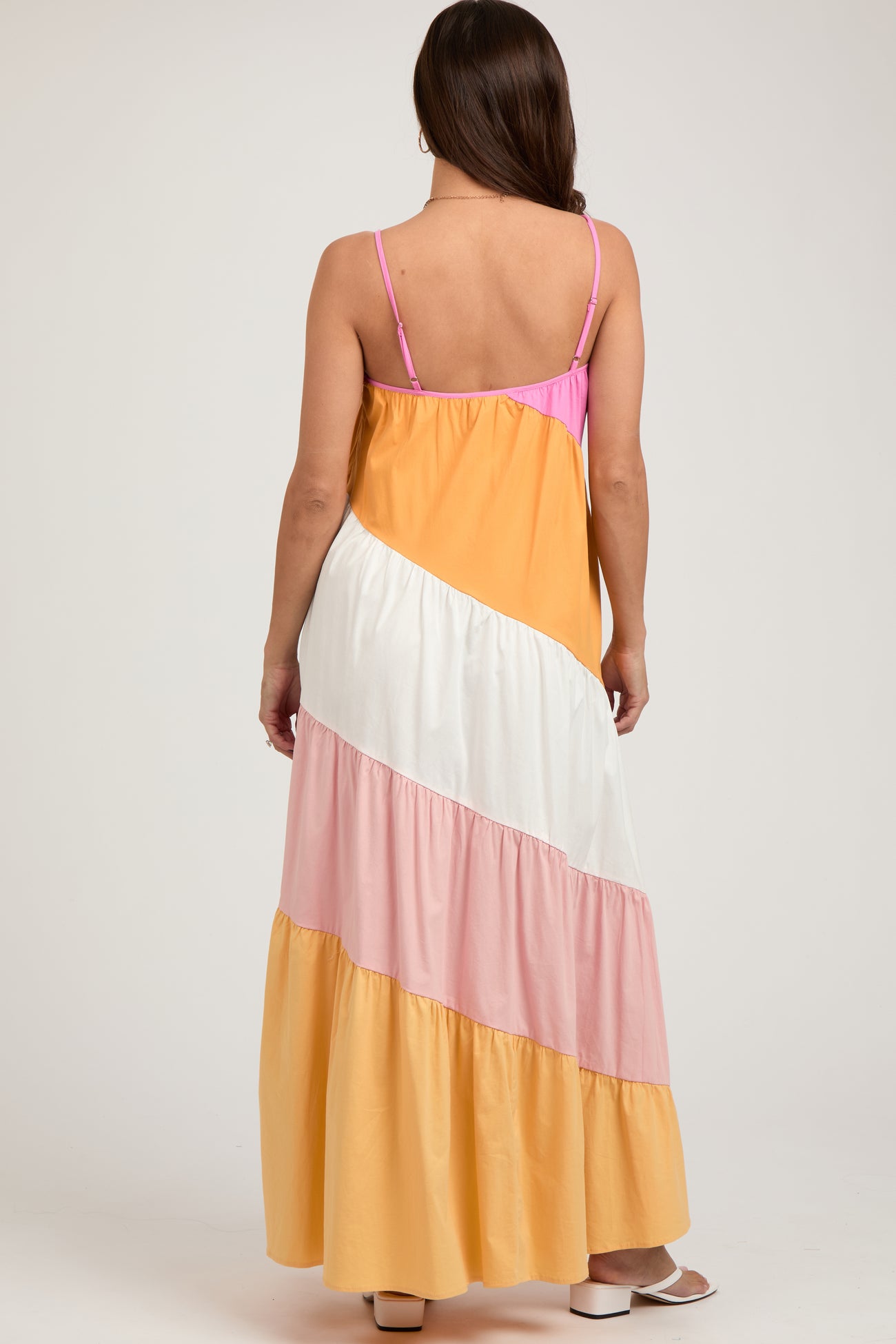 woman wearing a colorful striped maternity maxi dress with a tiered skirt and spaghetti straps, showing her back
